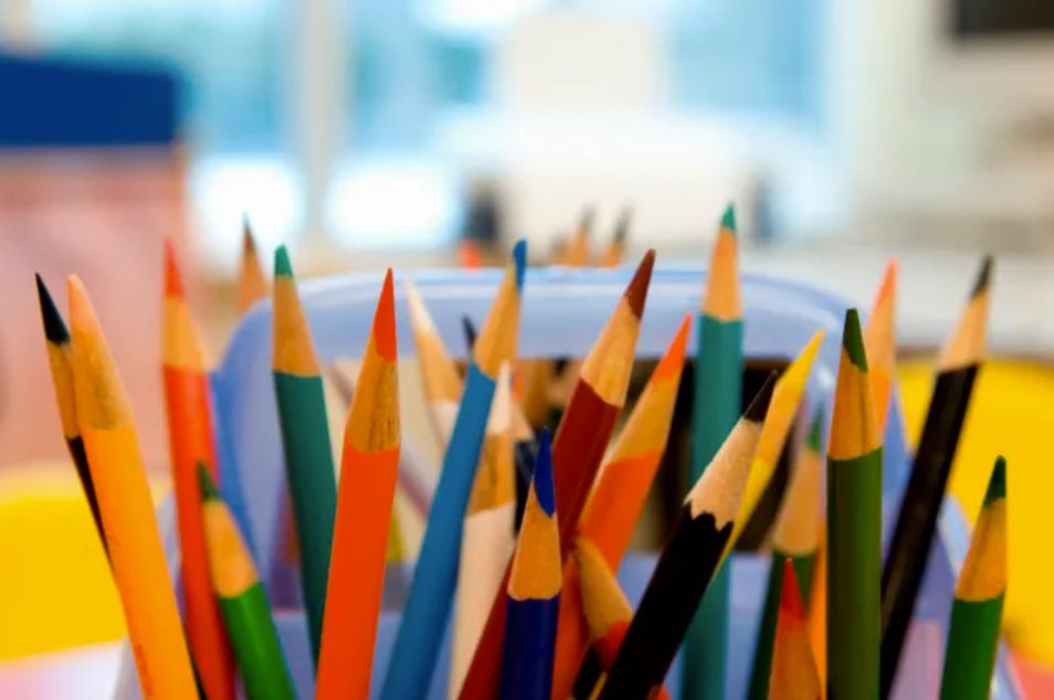 A close up of many colored pencils in a bowl